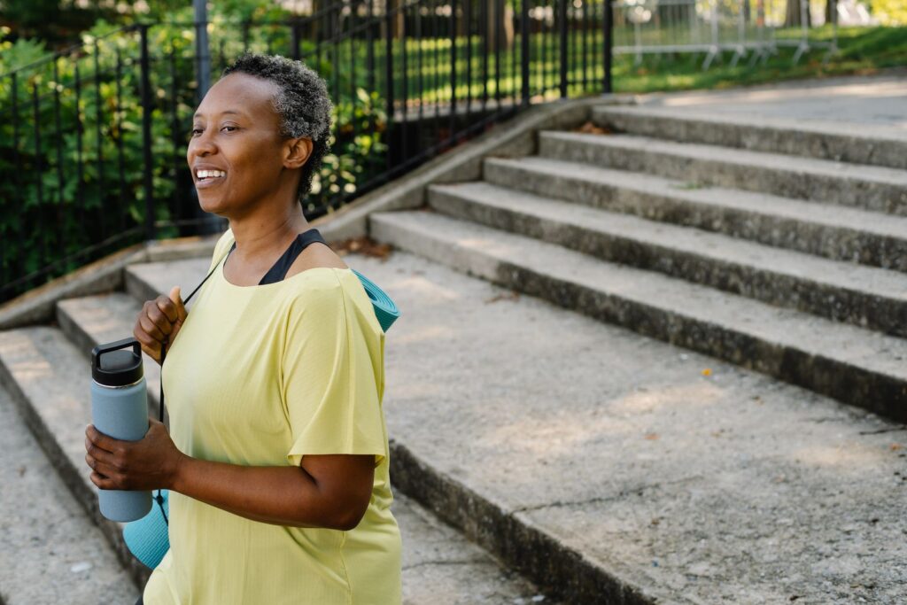 Woman exercising outdoors and smiling while holding a water bottle