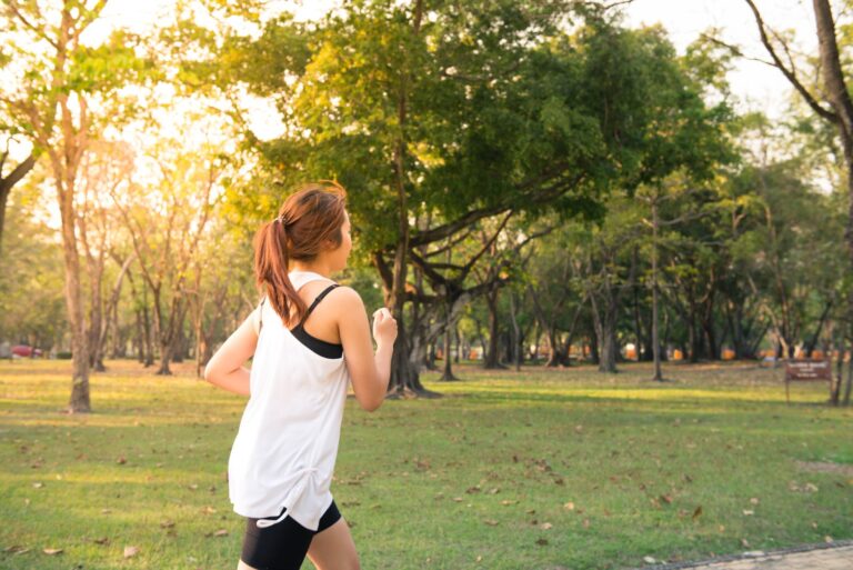 Woman jogging along a forest path in early morning sunlight