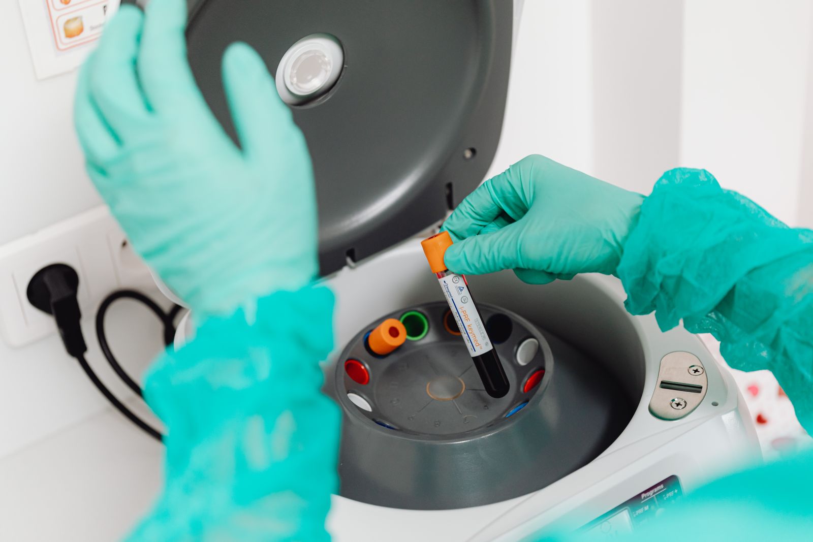 Lab technician in gloves operating a centrifuge during sample analysis