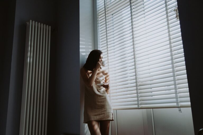 Woman standing in soft morning light beside a window
