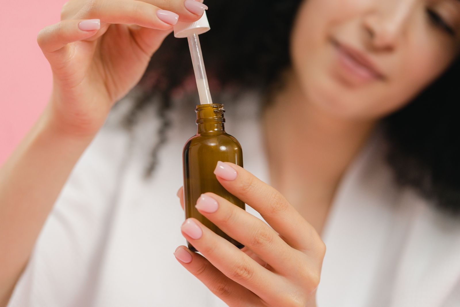 Woman applying serum from a dropper bottle