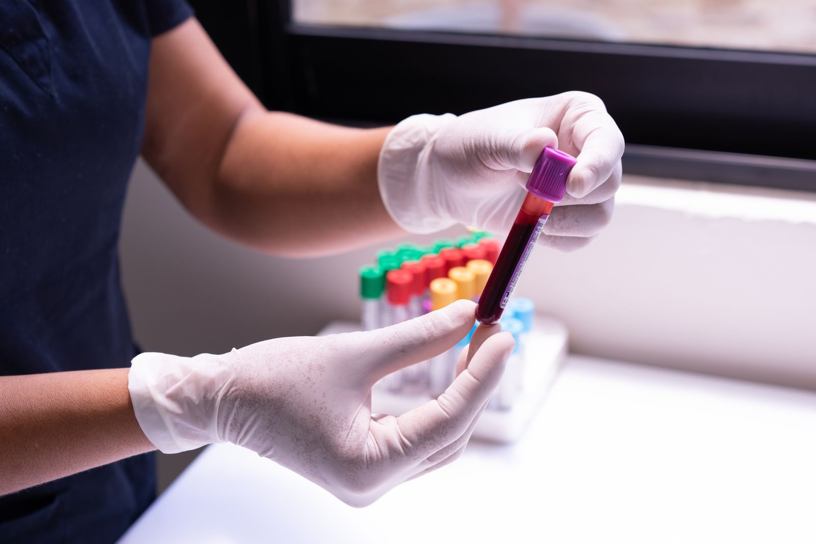 Gloved hands carefully handling a labeled sample tube in a laboratory