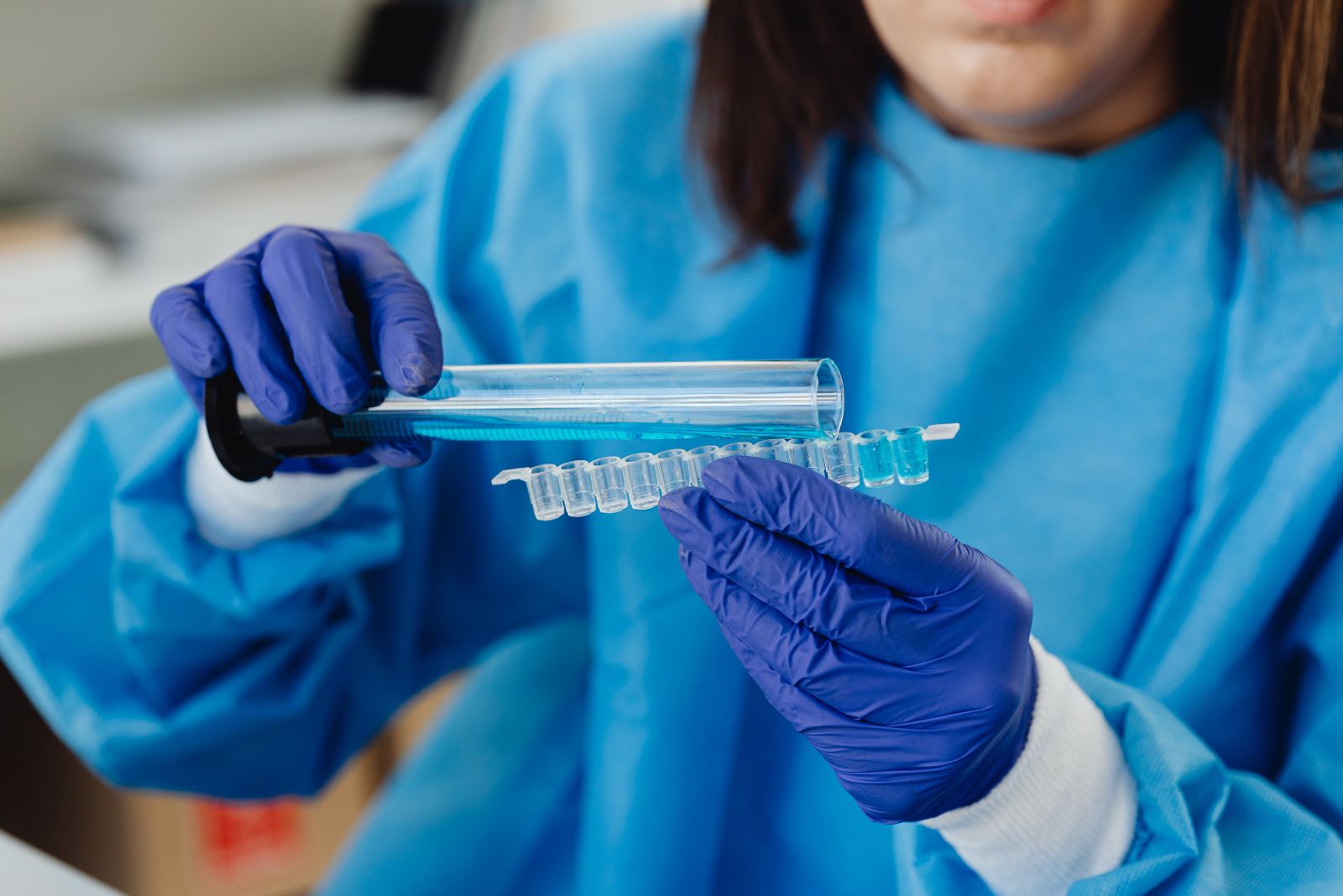 Scientist in protective gear running laboratory analysis with test tubes