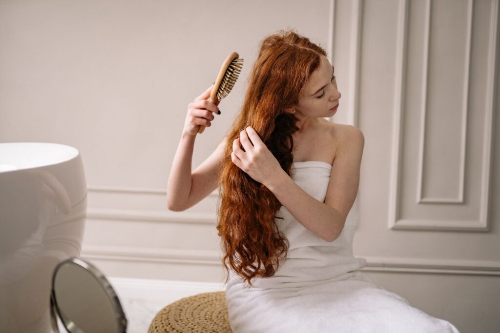 Woman with long red hair combing it after washing