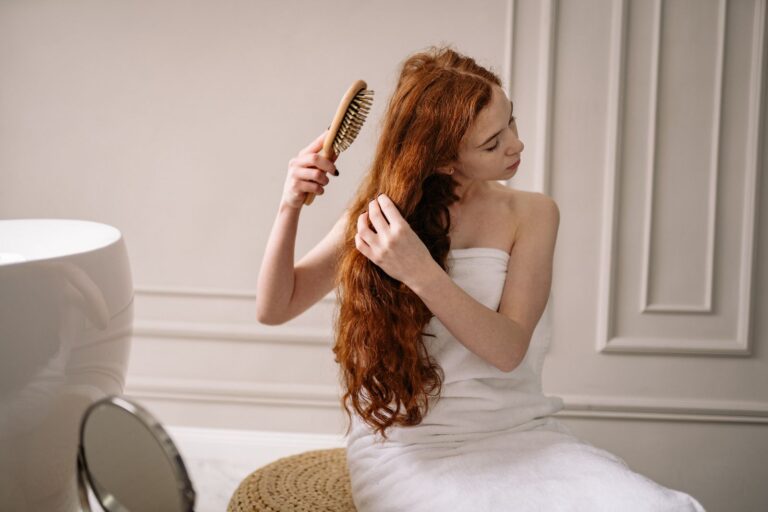 Woman with long red hair combing it after washing
