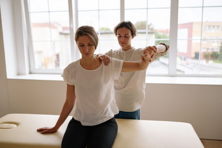 Therapist guiding a woman through an arm stretch during a rehabilitation session