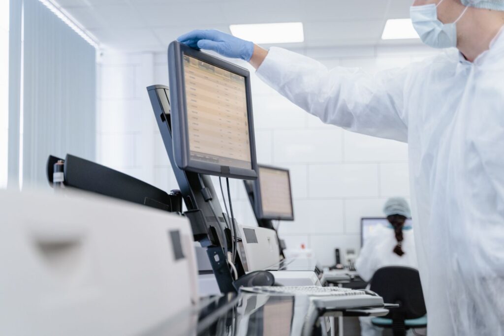 Researcher in protective gear reviewing data on a screen in a modern laboratory