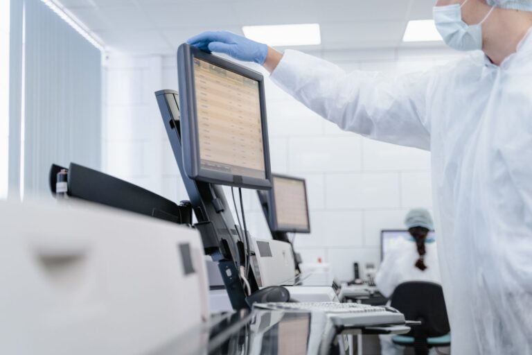 Researcher in protective gear reviewing data on a screen in a modern laboratory
