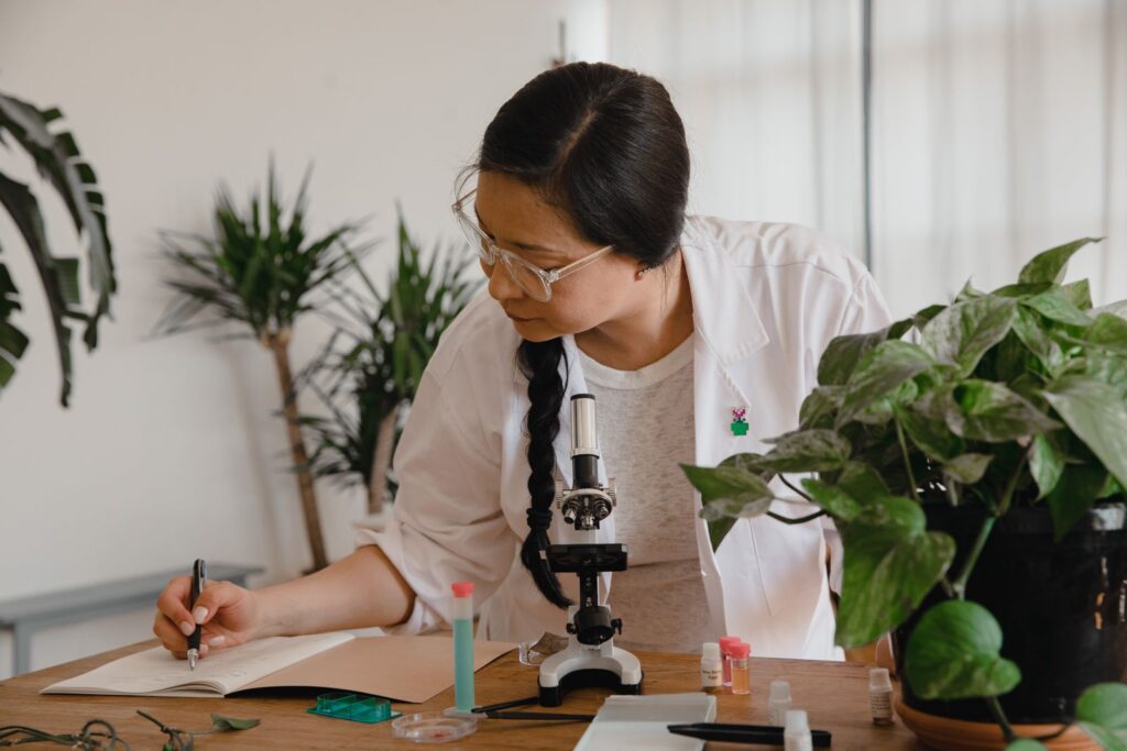 Female scientist taking notes beside a microscope in a laboratory