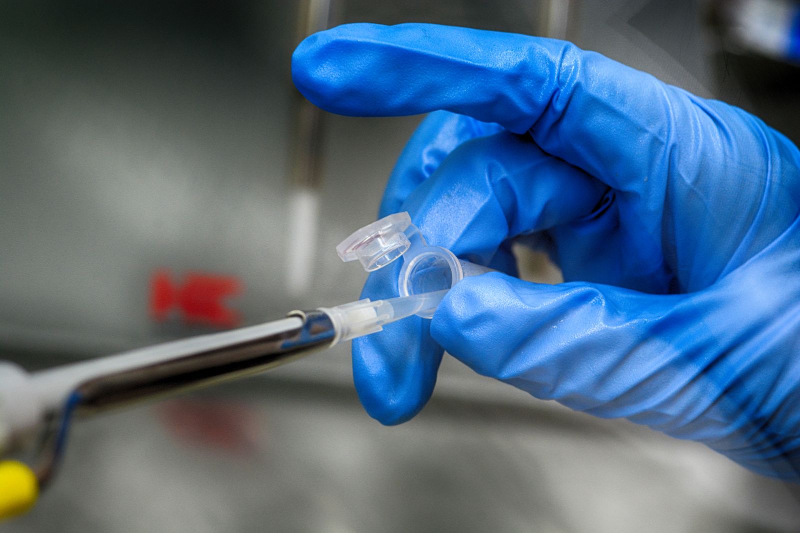 A scientist in blue gloves taking a sample in a laboratory