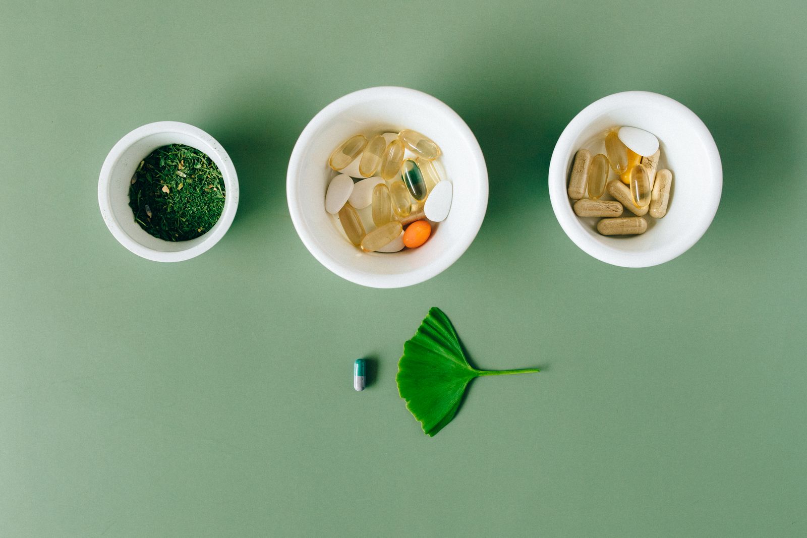 Capsules and dried herbs laid out in small bowls