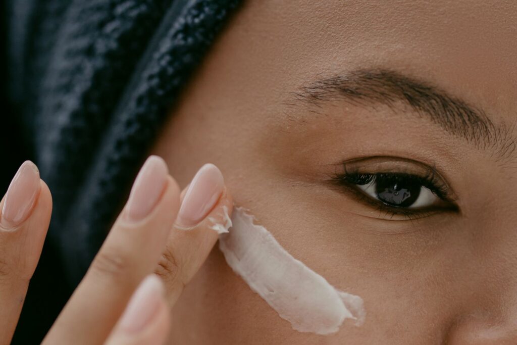 Close view of a woman applying cream to her cheek