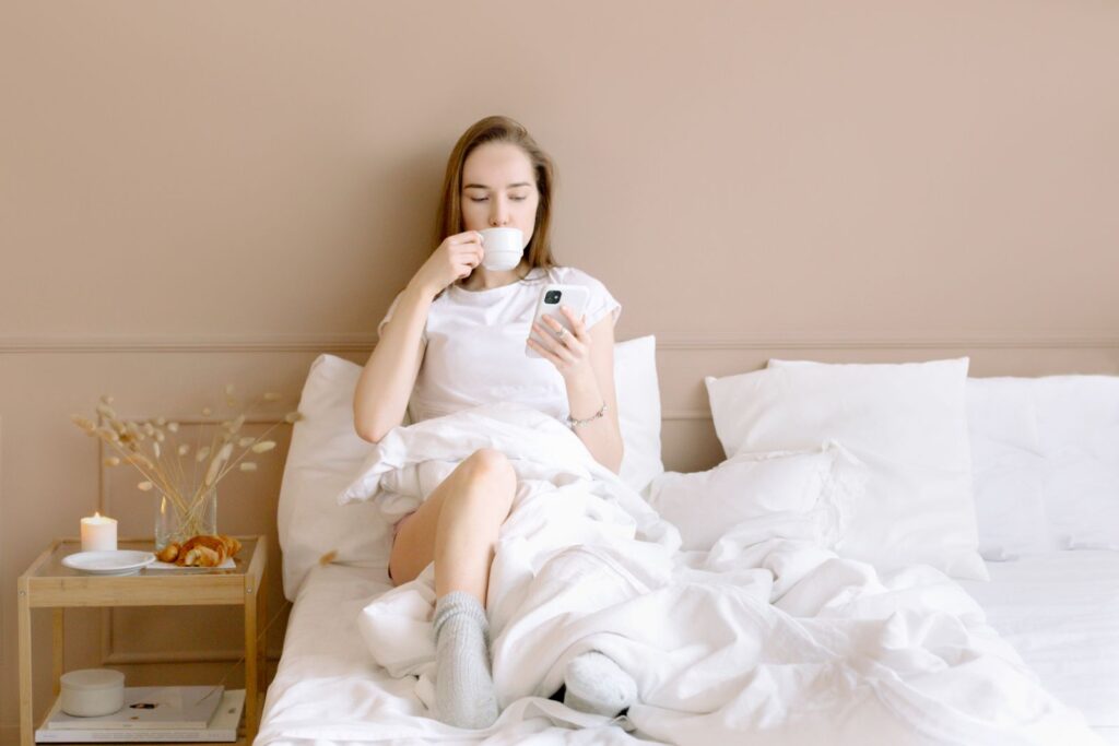 A woman relaxing in bed with a coffee