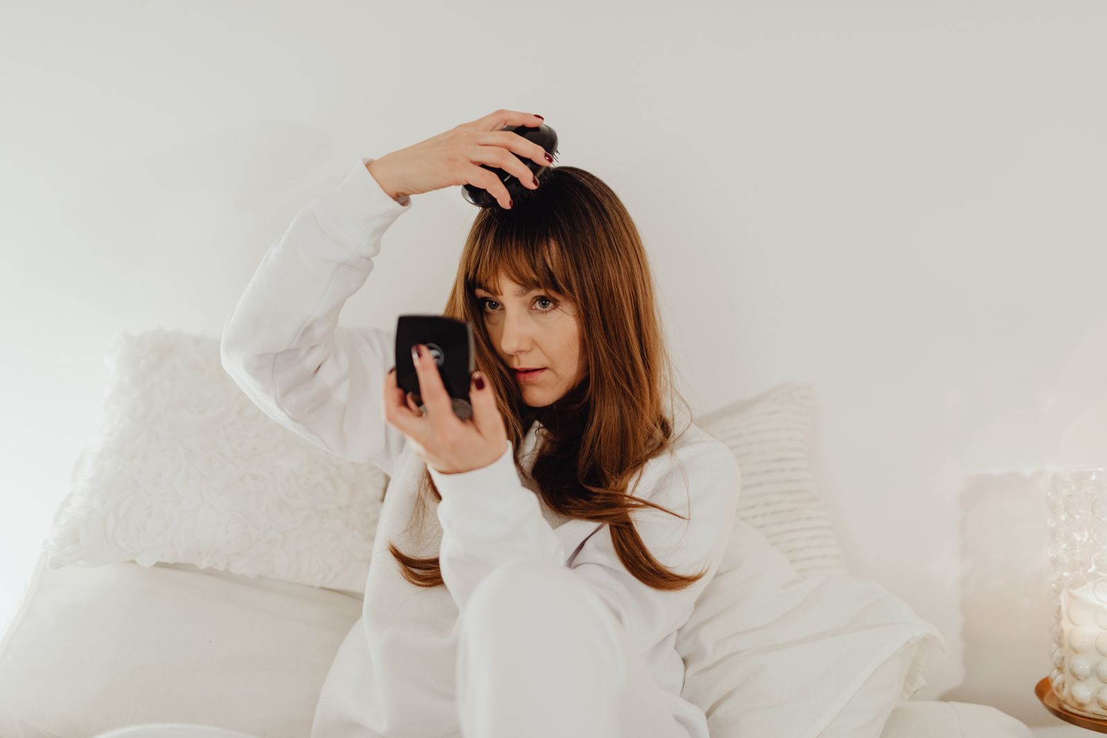 A woman combing her hair while seated in soft light
