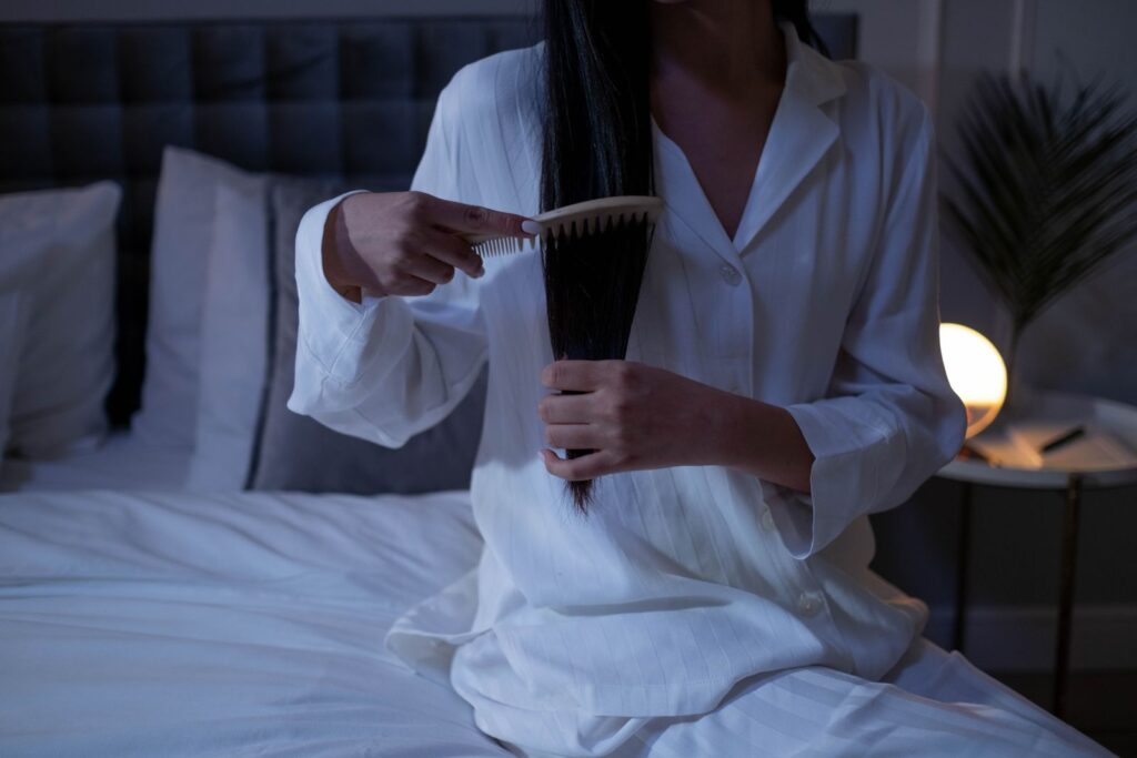 A woman combing long hair in a quiet bedroom