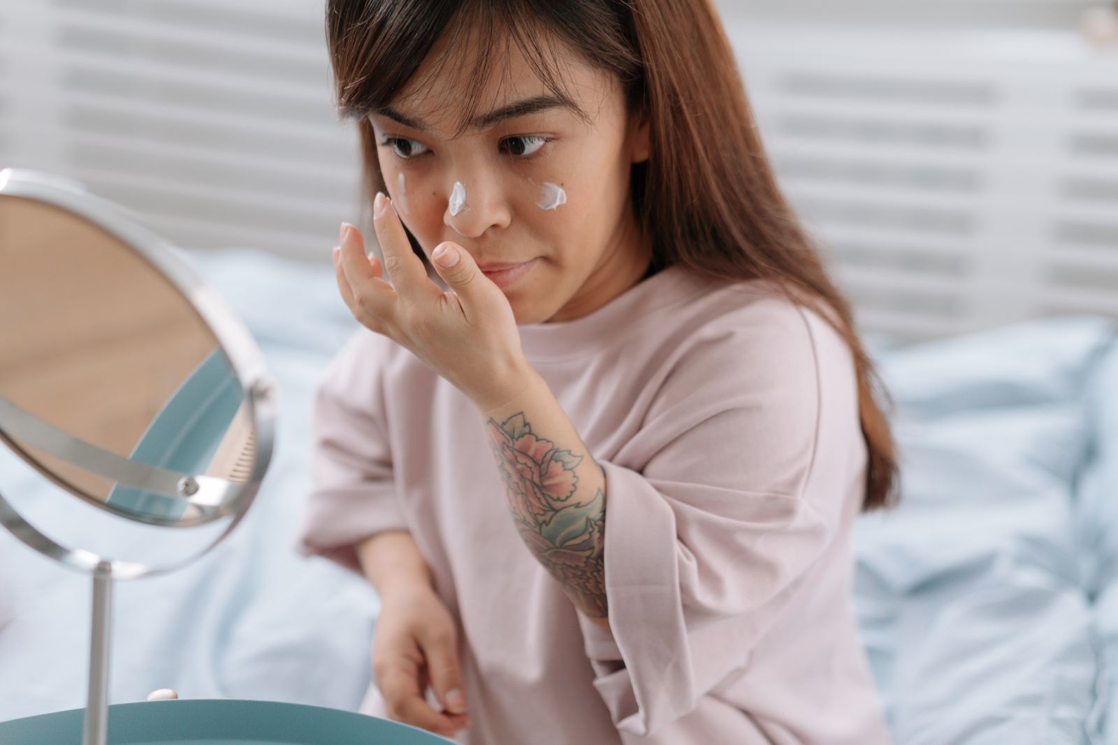 A woman applying face cream at home during a morning routine