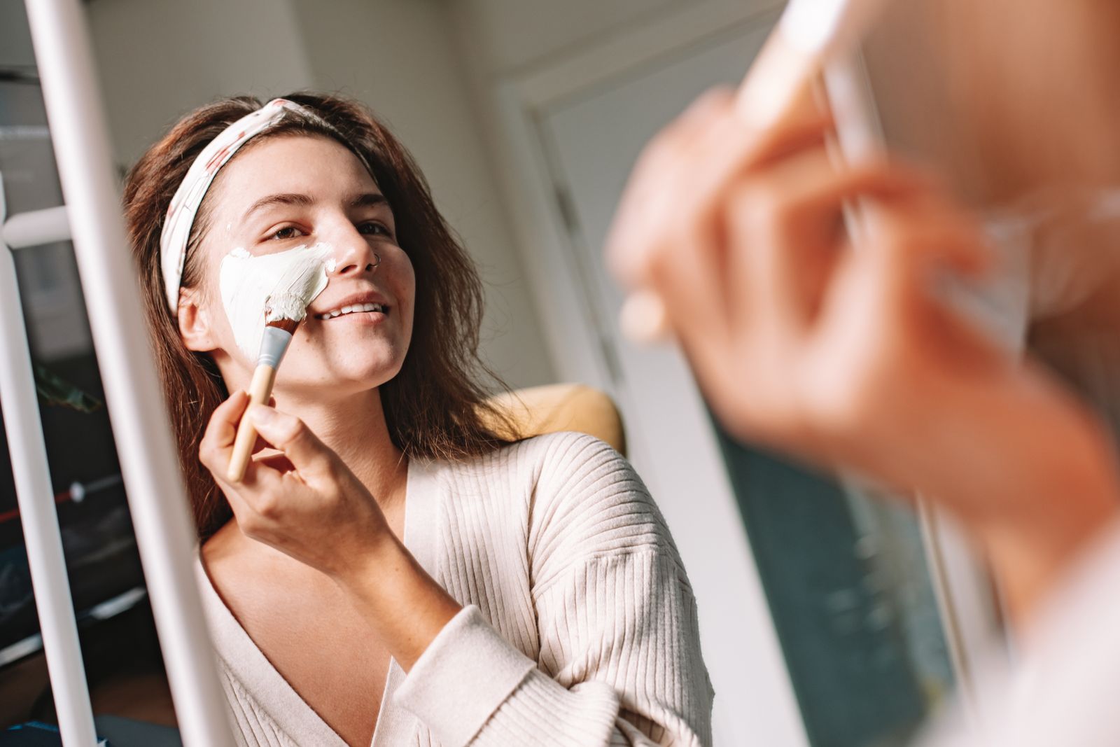 A woman applying a facial mask with a brush