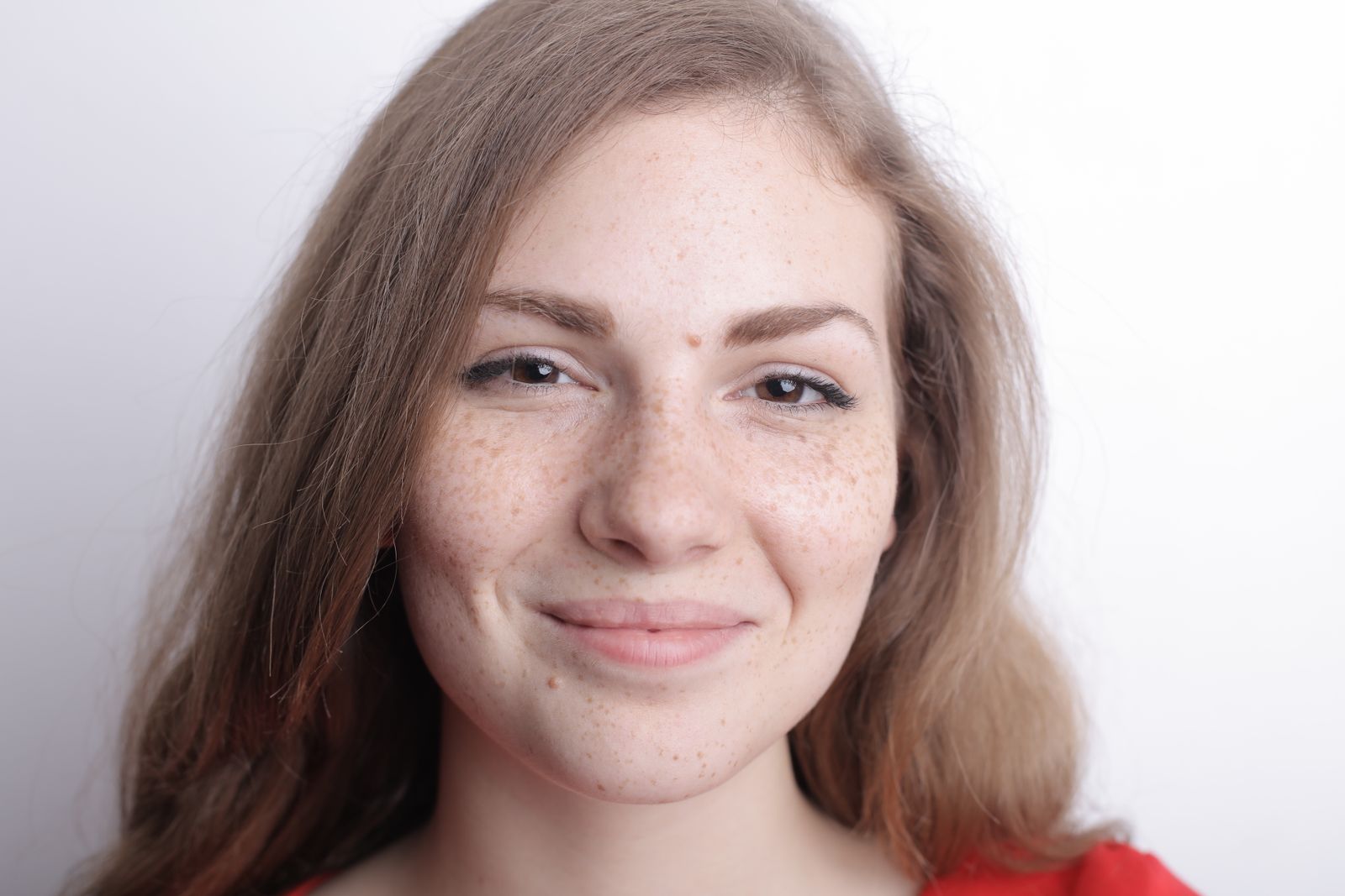 A smiling woman with freckles in natural light