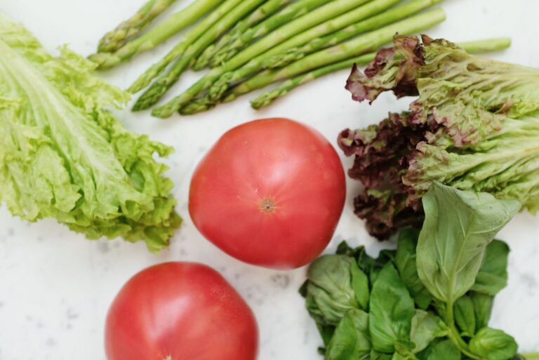 Fresh asparagus, lettuce and tomatoes laid out on a surface