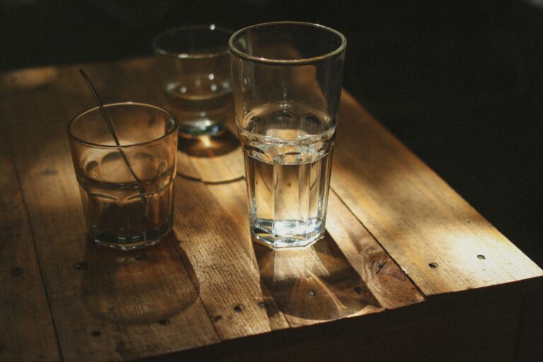 Drinking glasses casting shadows on a wooden table