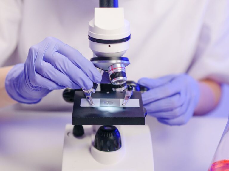 A researcher in gloves using a microscope in a laboratory