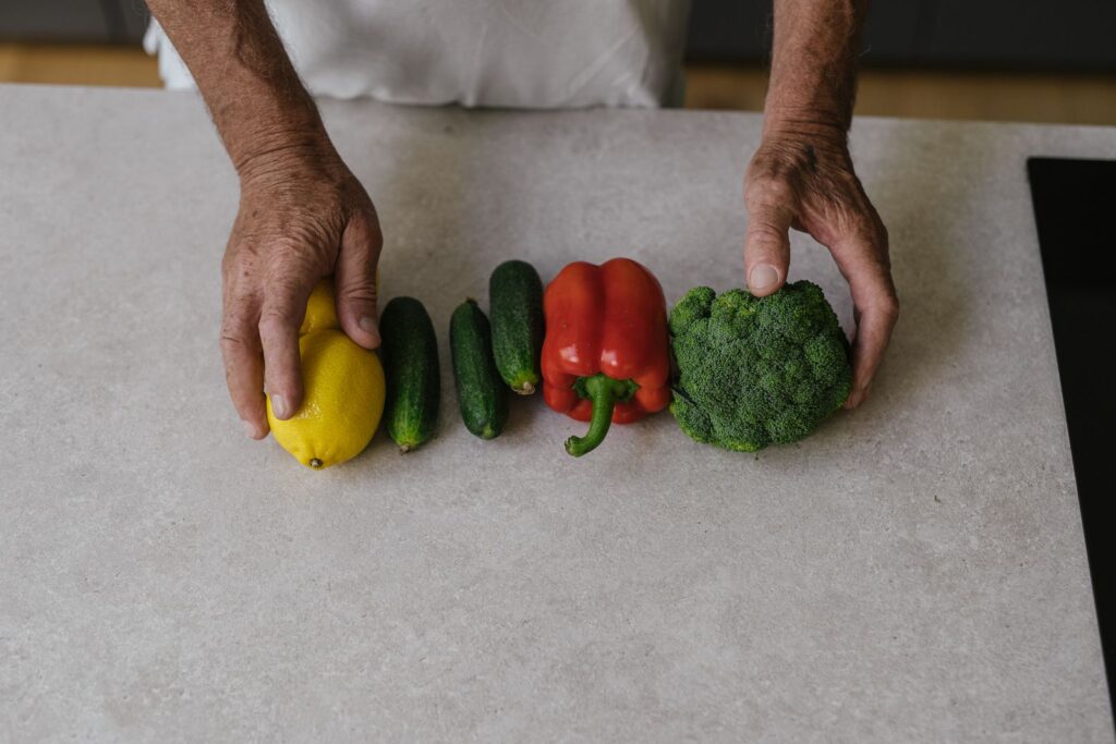 Hands arranging fresh vegetables on a kitchen counter