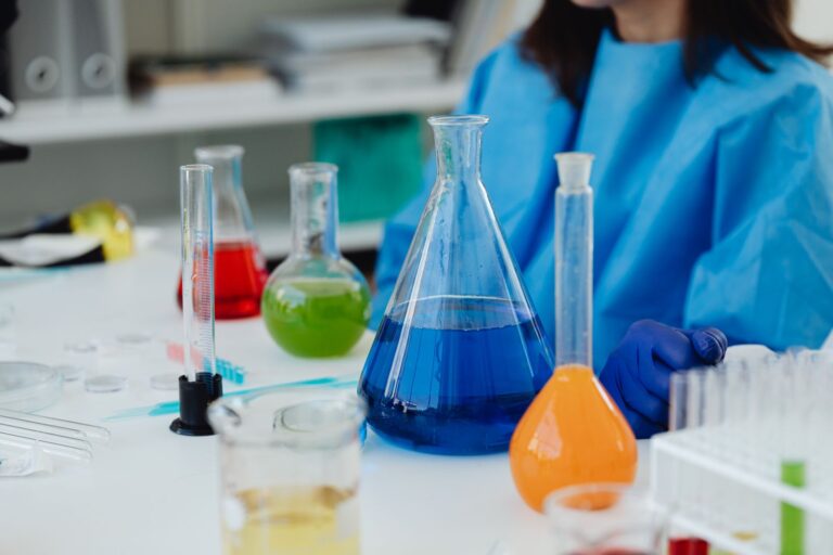 A laboratory desk holding glassware and coloured chemical solutions
