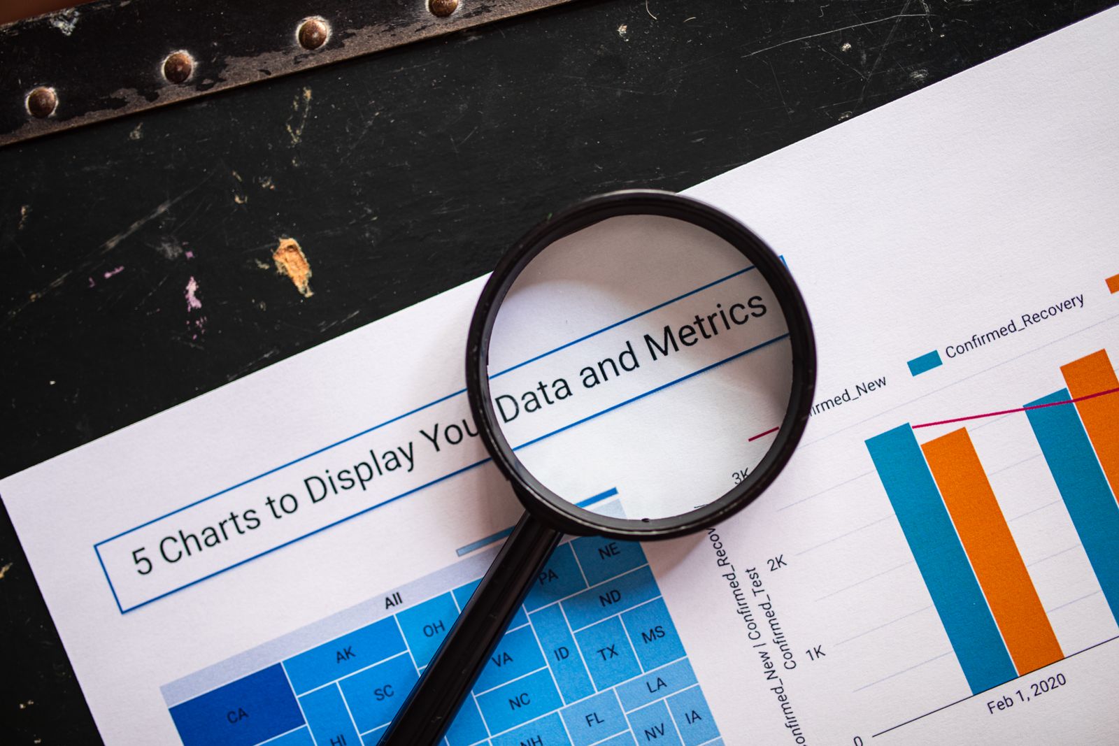 A magnifying glass held over printed data charts