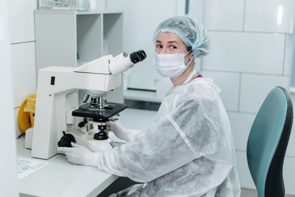 A researcher using a microscope in a sterile laboratory environment