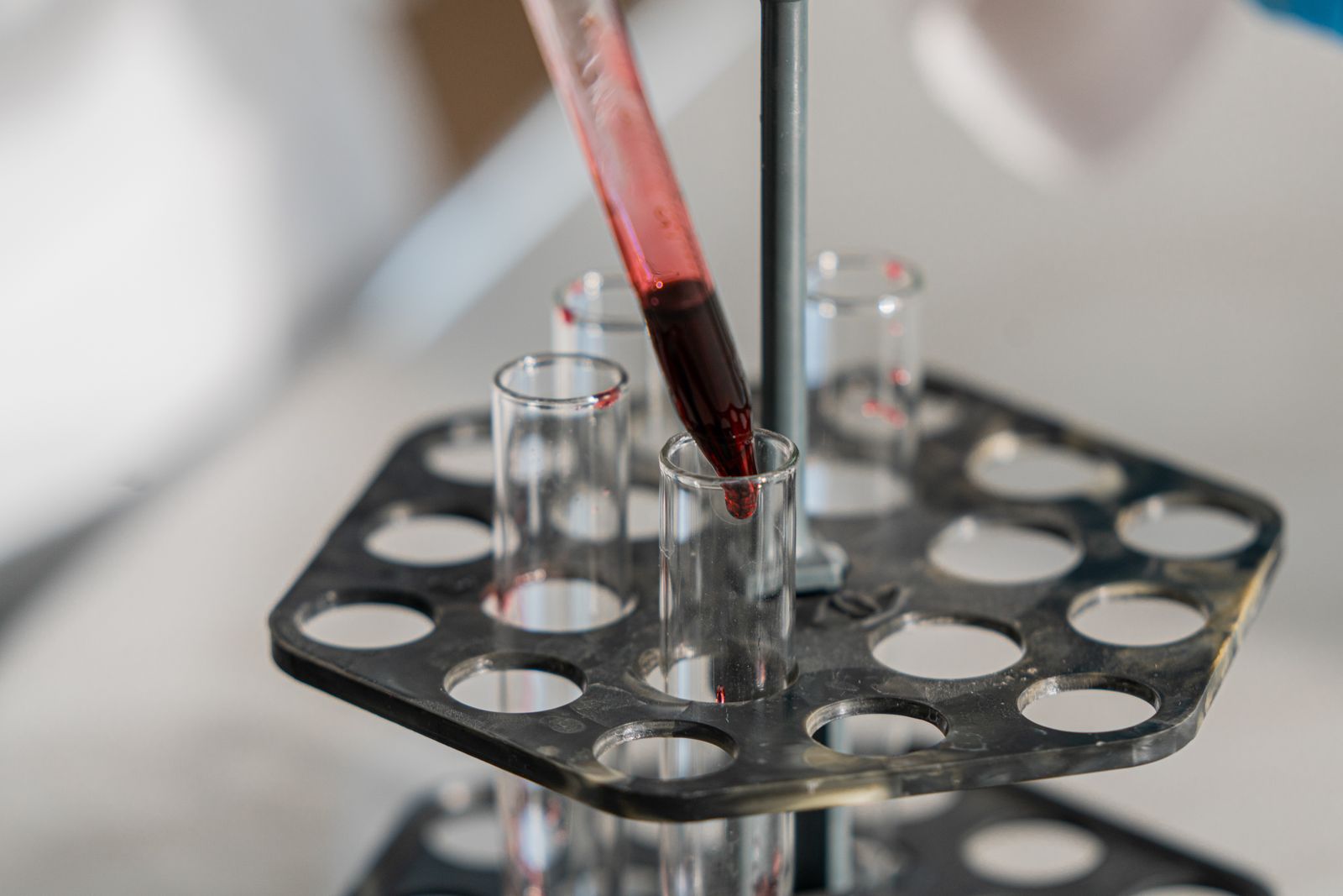 Red solution being transferred into test tubes in a laboratory