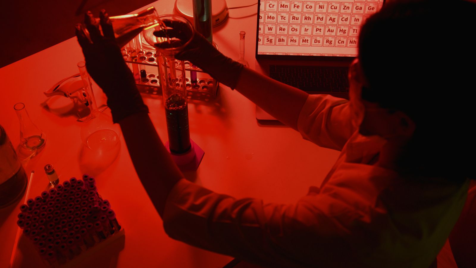 A researcher conducting an experiment in a red-lit laboratory