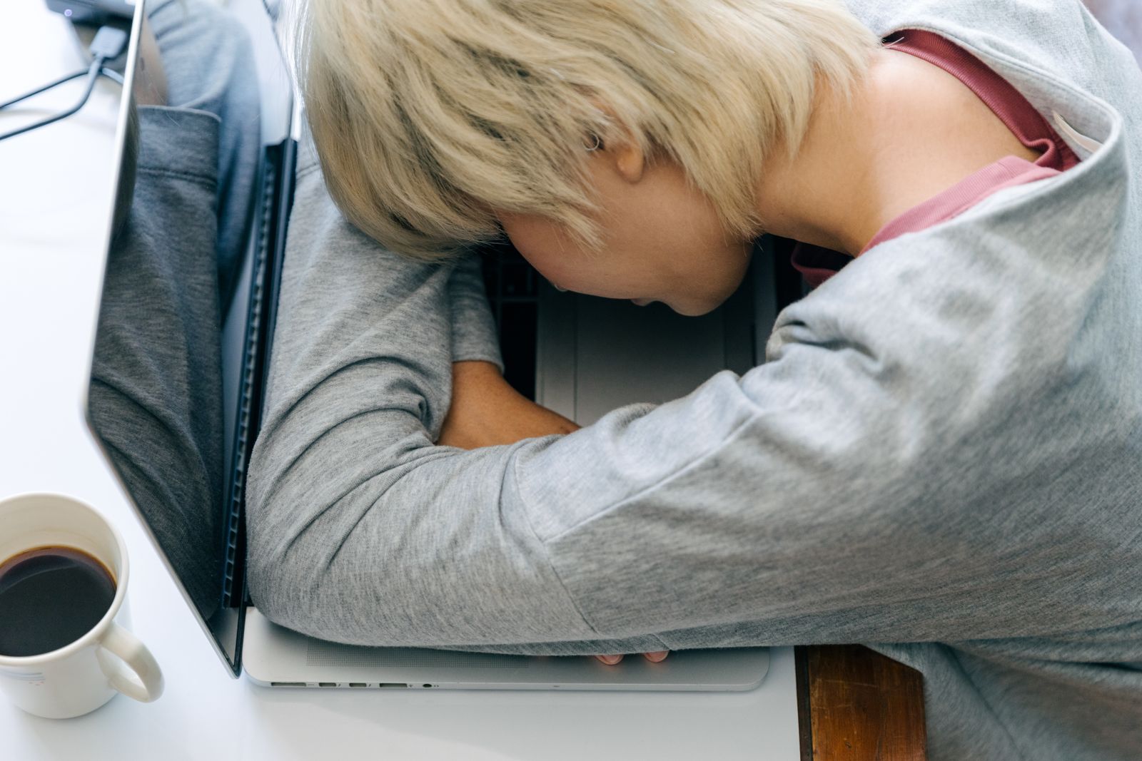 A woman resting her head beside a laptop