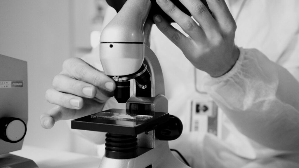 A scientist in a lab coat using a microscope for sample analysis