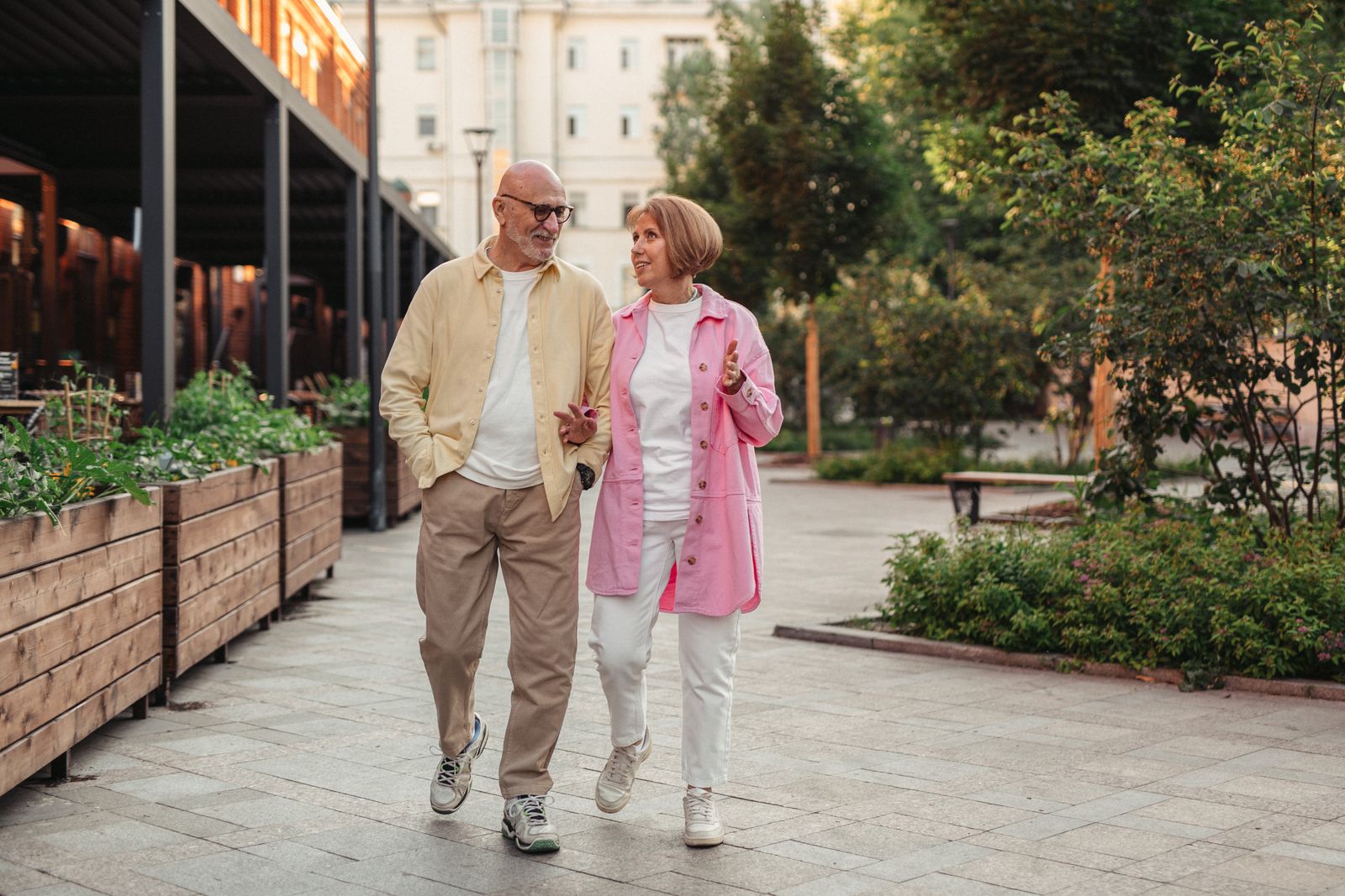 Two older people walking together in a green urban setting