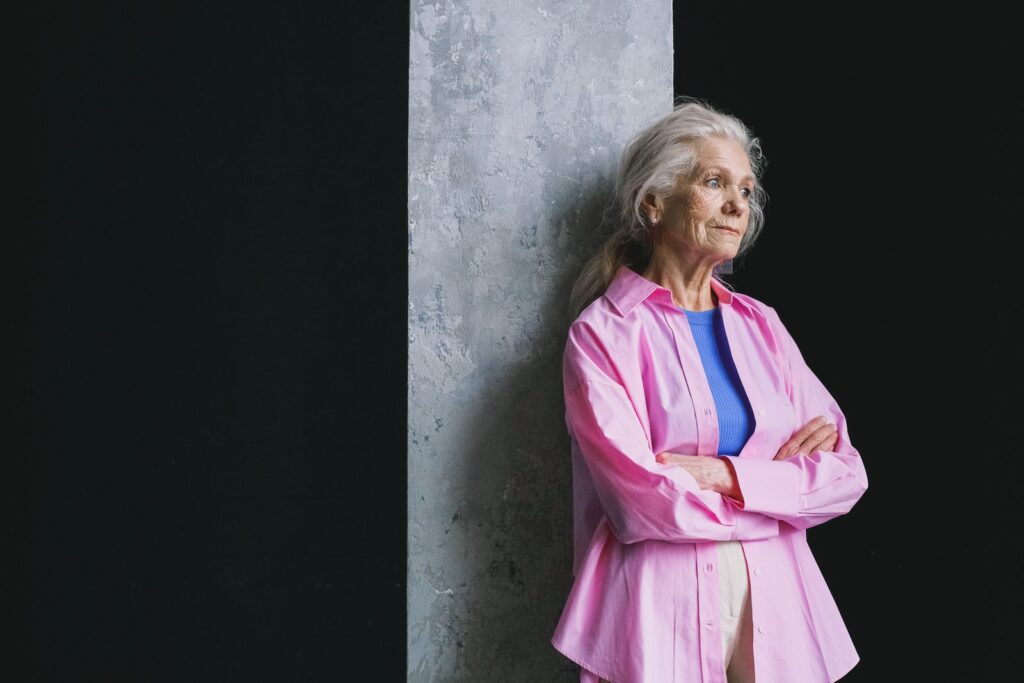 An older woman with grey hair standing with her arms crossed