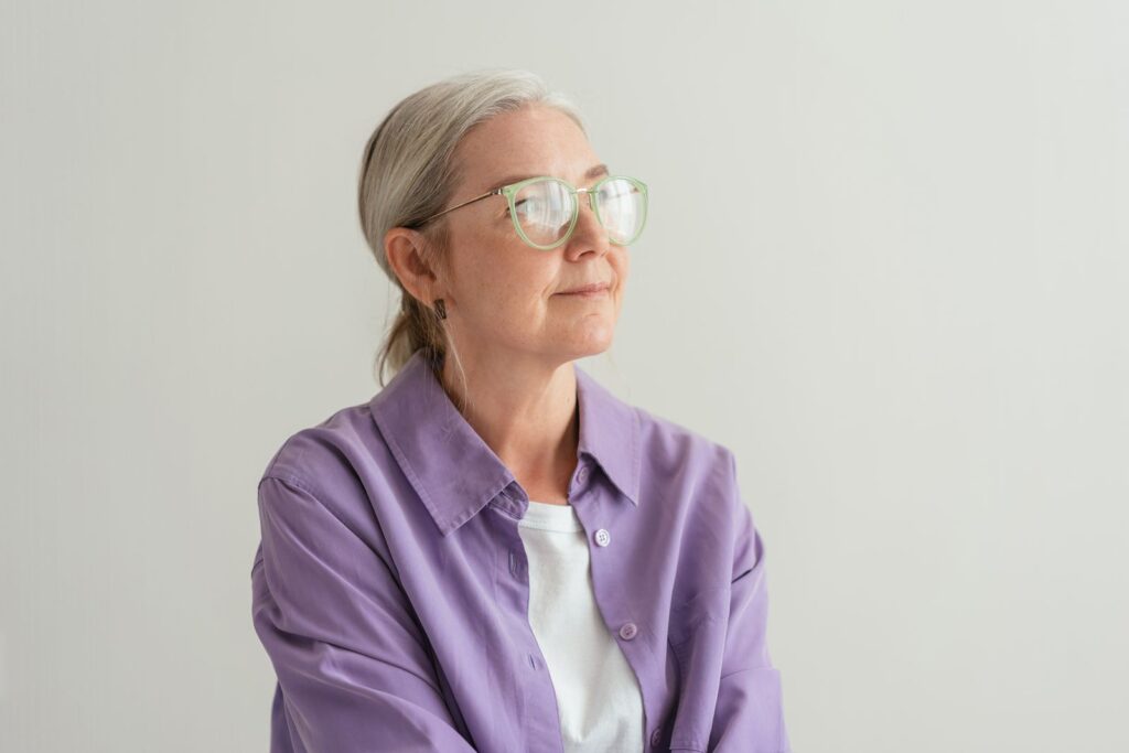 A woman with grey hair and glasses looking thoughtful