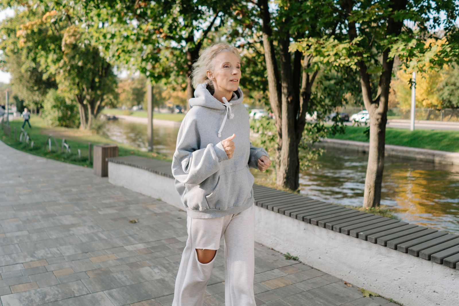 An older woman jogging along a park pathway