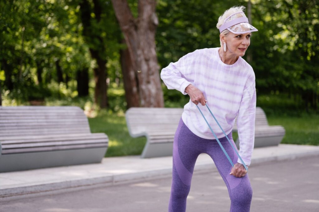 A woman using a resistance band during an outdoor workout in a park
