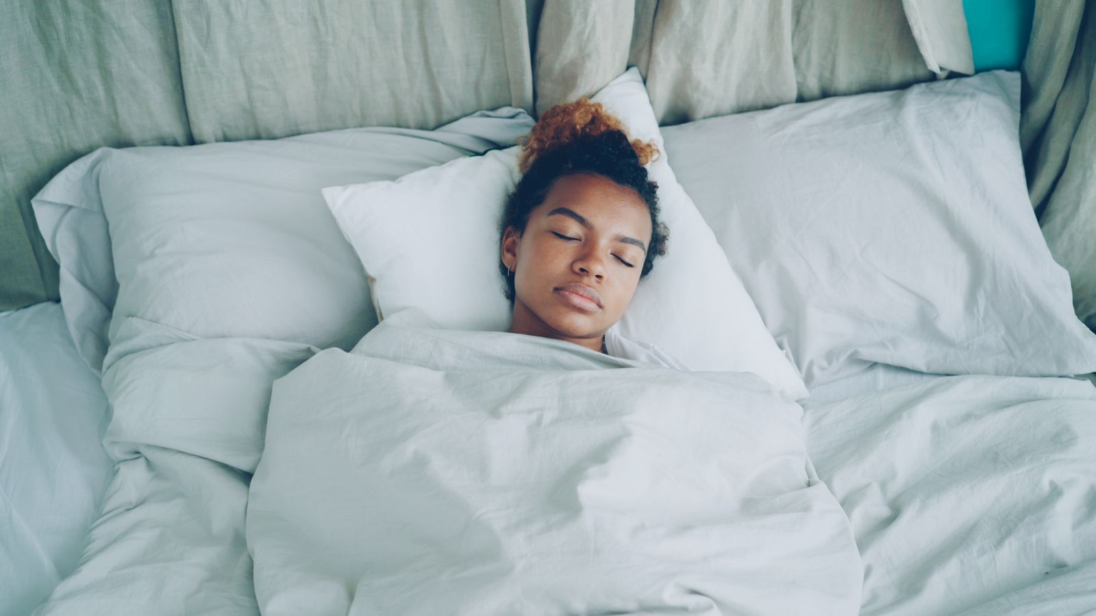 A woman sleeping peacefully in a bed with white sheets