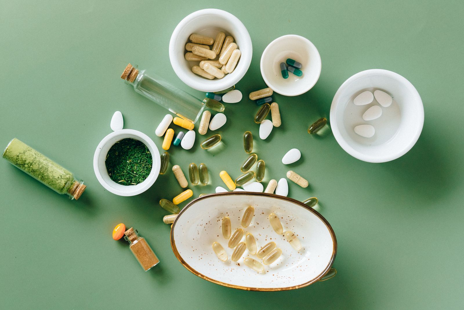 Assorted capsules and herbs arranged in ceramic bowls