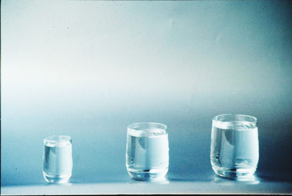 Three glasses of clear water on a plain surface
