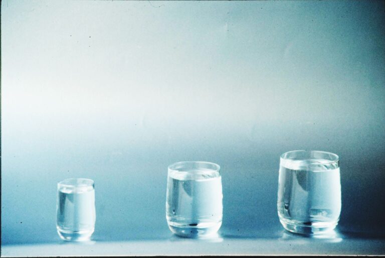 Three glasses of clear water on a plain surface