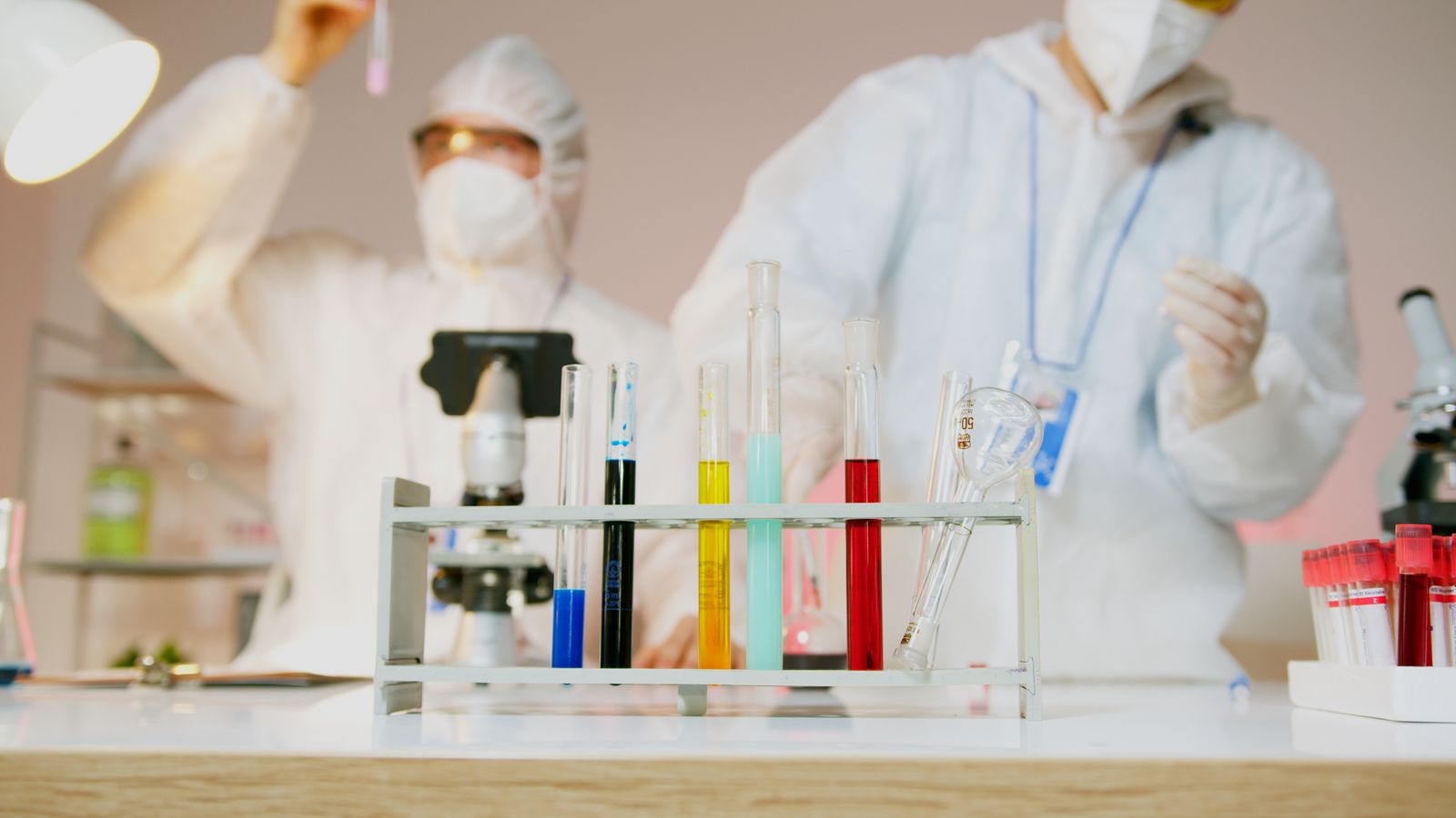 Two researchers in protective gear working with test tubes