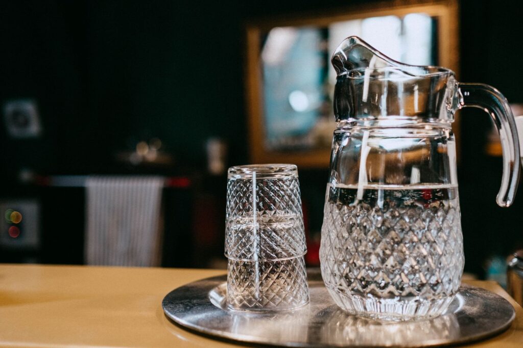 A glass pitcher and tumblers filled with clear water