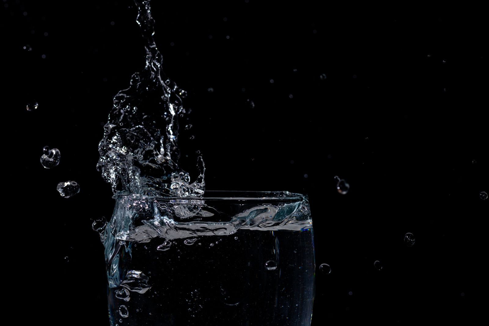 Clear water splashing inside a glass against a dark background