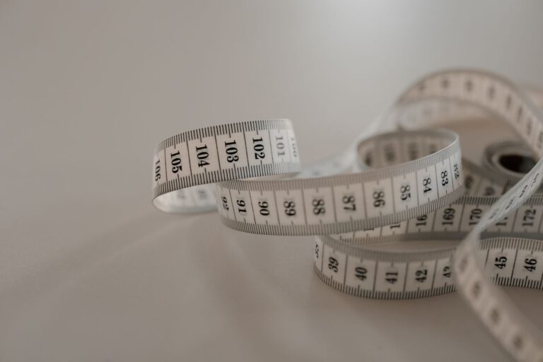 A white tape measure coiled on a plain surface