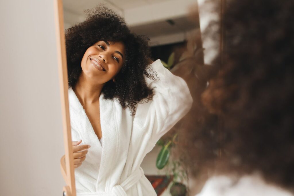 A woman with curly hair smiling at home in a bathrobe