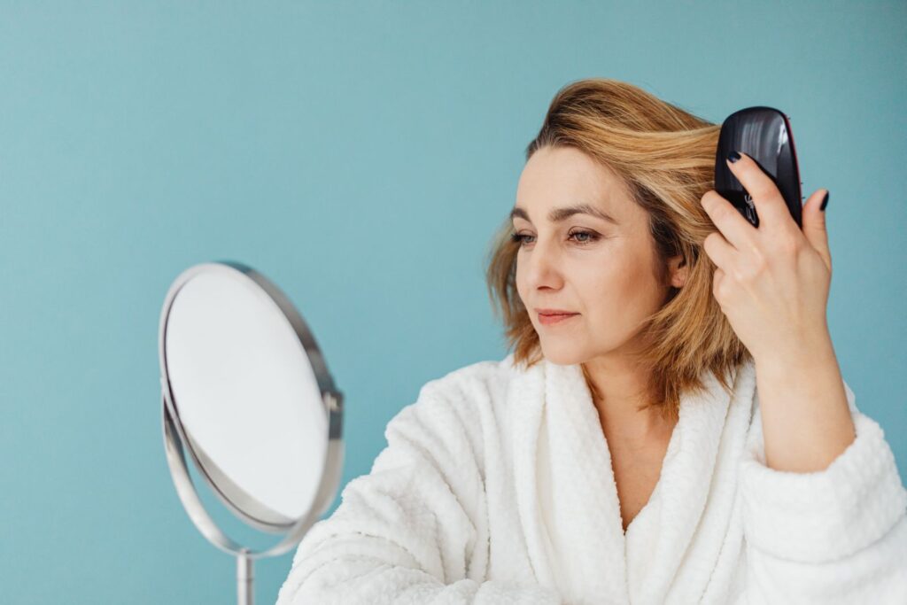 A woman combing her hair calmly in front of a mirror