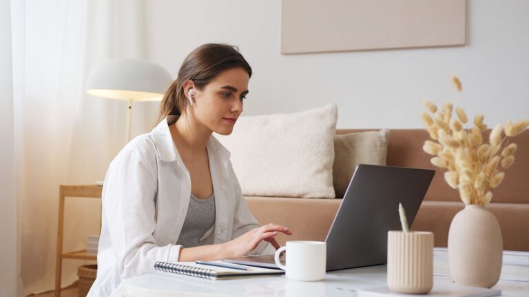 A woman in casual clothes browsing on a laptop at home
