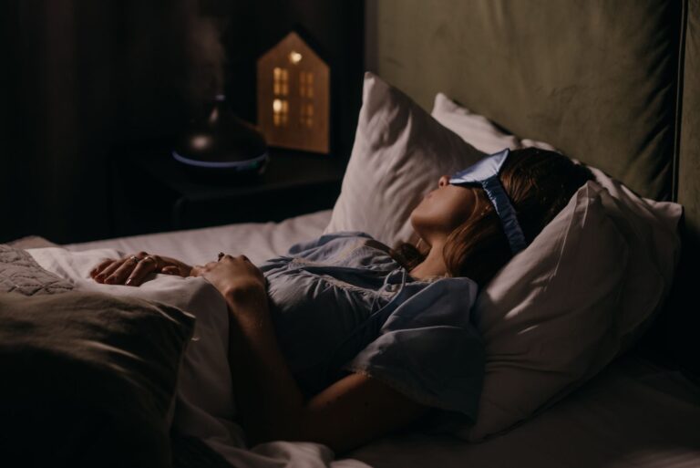 A woman sleeping with an eye mask in a dimly lit bedroom